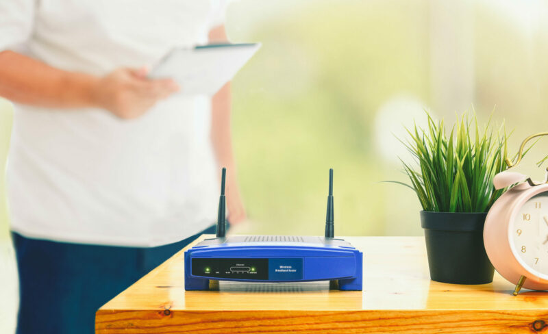 closeup of a wireless router and a man using smartphone on livin
